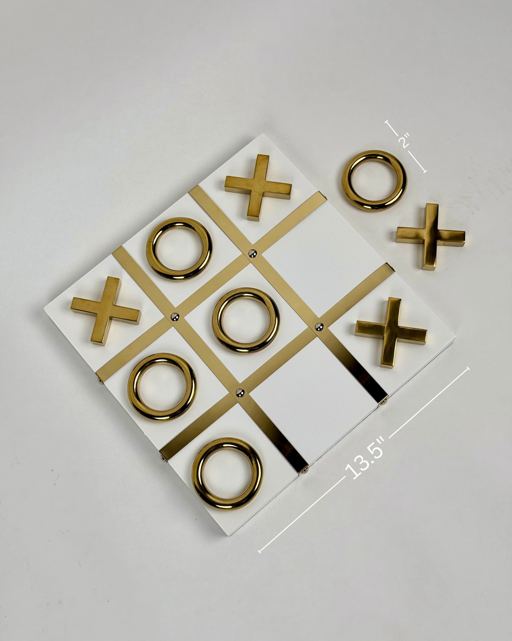 High Objects gold and white tic-tac-toe set with gold iron pieces on a white MDF board. Modern decor.