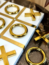 High Objects gold-tone iron tic-tac-toe set with white MDF board. Sculptural X and O pieces.