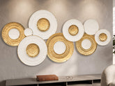High Objects decorative wall art featuring a cluster of circular white and gold textured metal plates on a beige wall.