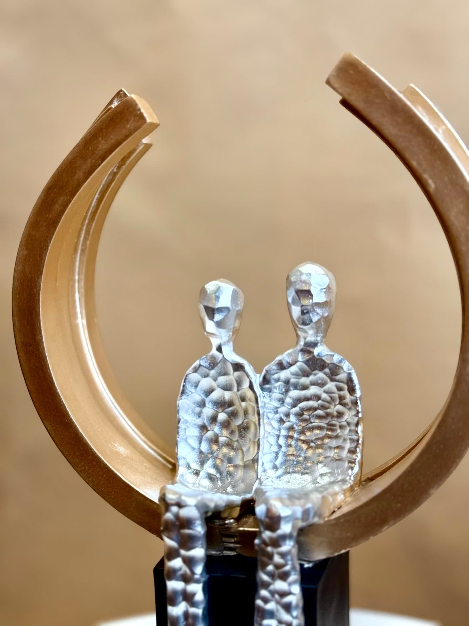 High Objects Golden Arc of Love showpiece with hammered silver finish couple in a gold ring on black base.