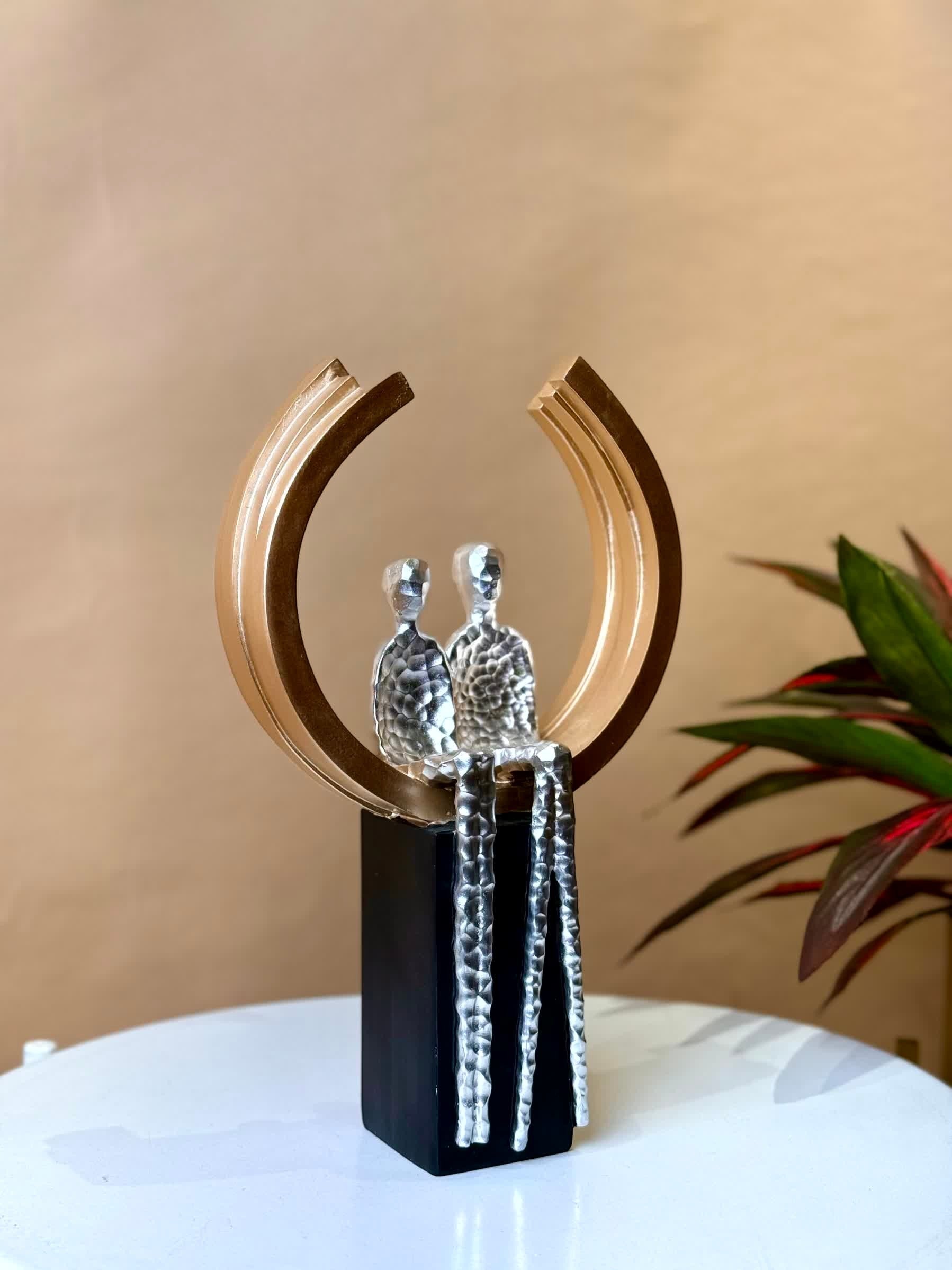 High Objects Golden Arc of Love showpiece, abstract couple in hammered silver finish within a gold ring on a black base.