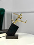 High Objects Golden Hurdler Leap Artefact sculpture, polished gold figure mid-flight on a black angled pedestal.