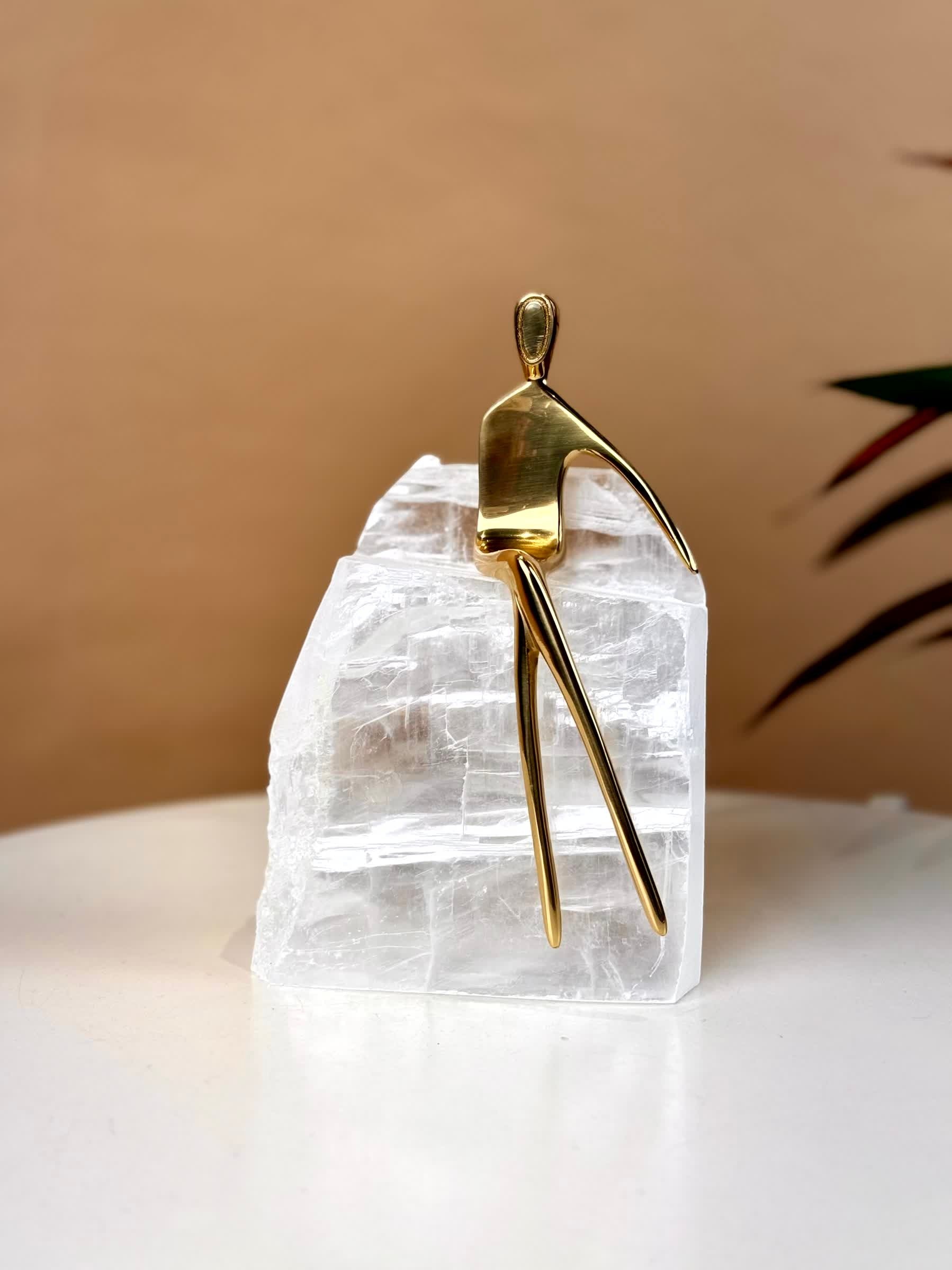 High Objects Golden Poise abstract sculpture on a natural crystal base. Polished gold-finished iron figure.