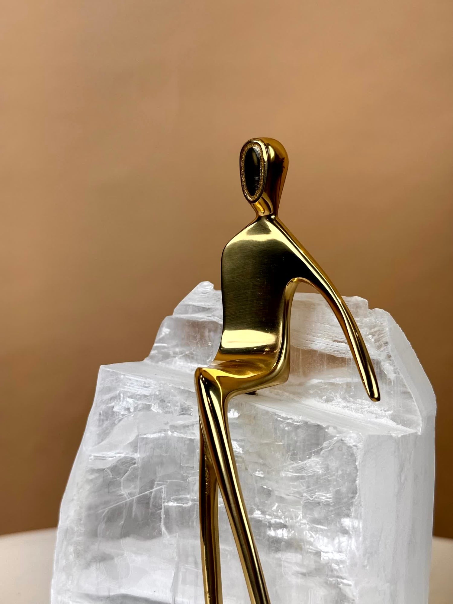 High Objects Golden Poise abstract figure sculpture made of polished gold-finished iron on a natural crystal base.