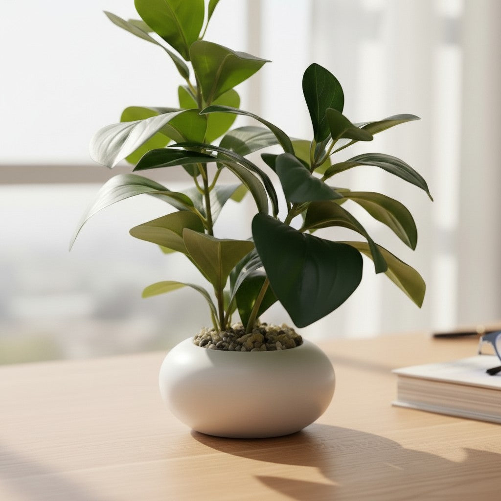 High Objects green artificial plant in a white ceramic pot with pebbles, on a wooden desk with a book and glasses.