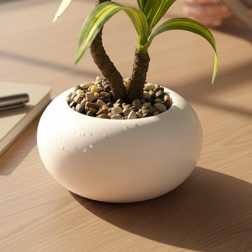 High Objects white ceramic pot with a green and yellow striped plant, on a wooden desk next to a notebook and pen.