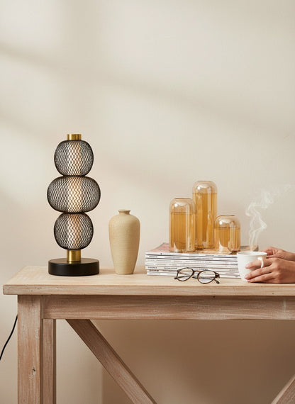High Objects Complete Home Ambience Decor Set: black mesh lamp, beige vase, potted plant, and amber glass candle holders on magazines.