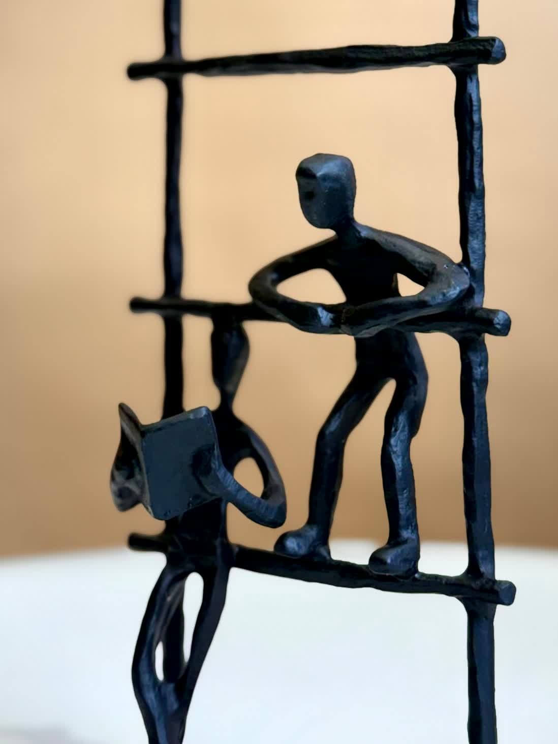 High Objects abstract iron figurine of three figures on a ladder, symbolizing growth and connection. Matte black finish.