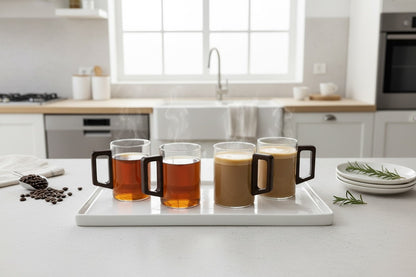 High Objects LINEA™ set of 4 clear glass cups with dark square handles, two filled with tea and two with coffee.