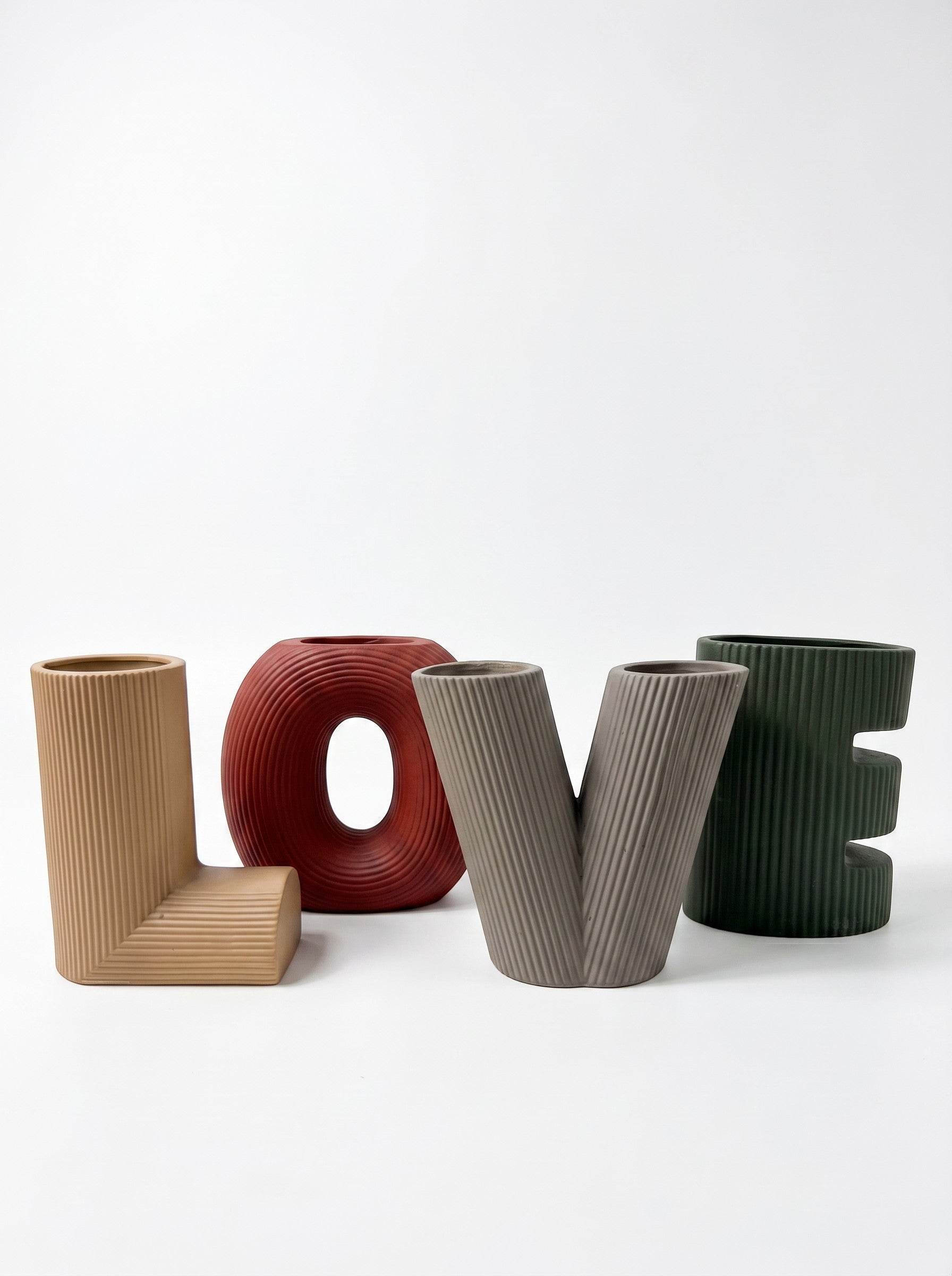 High Objects set of four decorative vases in the shape of the letters L, O, V, and E. Colors include tan, deep red, grey, and forest green.