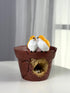 High Objects rustic cracked pot planter with two yellow and white lovebirds perched on the rim and a nest with eggs inside.