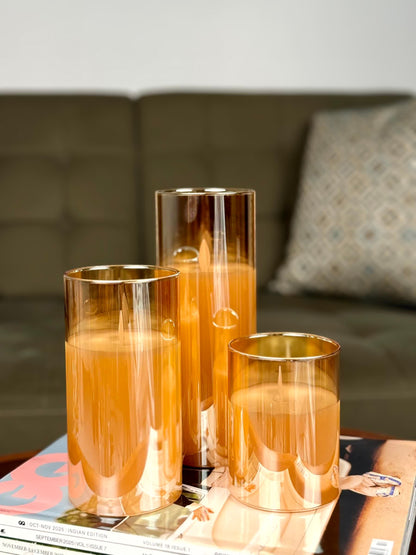 High Objects Lumiglass LED candles in amber glass cylinders, set of 3, on a stack of magazines.