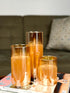 High Objects Lumiglass LED candles in amber glass cylinders, set of 3, on a stack of magazines.