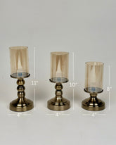 High Objects Luminaria Pedestal Candle Stand Set, antique brass metal with amber glass hurricanes, set of 3 heights 8", 10", 11"