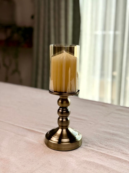 High Objects Luminaria Pedestal Candle Stand Set with tinted glass hurricane and metallic stem, antique brass finish.