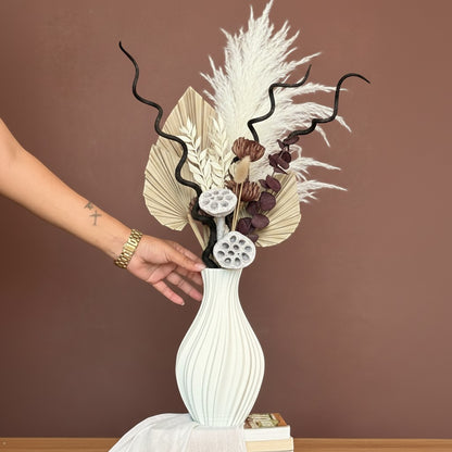 High Objects Lunara Vase, a white ribbed ceramic vase with a dried floral arrangement. Features pampas grass, palm leaves, and lotus pods.