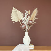 High Objects Lunara Vase, a white ceramic vase with a ribbed pattern, holding dried eucalyptus and pampas grass.