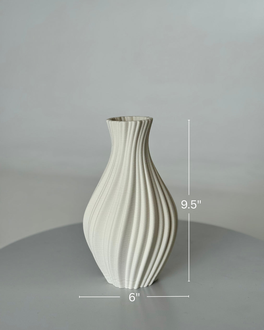 High Objects Lunara Vase, a matte white ceramic vase with a ribbed, flowing pattern and curved silhouette.