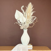 High Objects Lunara Vase, a white ceramic vase with a ribbed pattern, holding dried flowers.