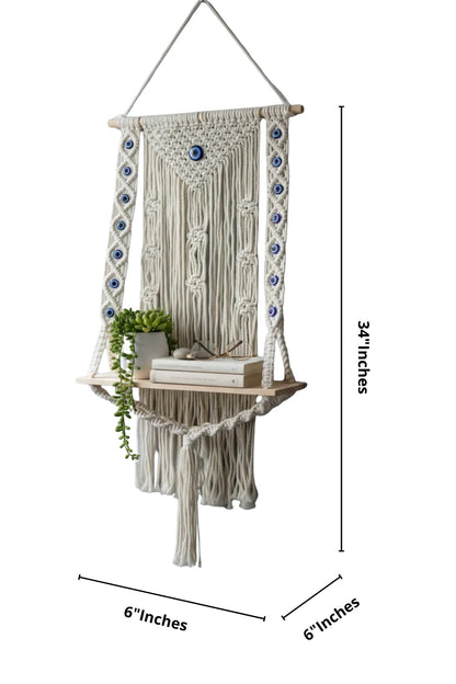 High Objects NazarGuard Boho Macrame Shelf with blue evil eye details, handmade cotton rope and wooden shelf holding books and a plant.
