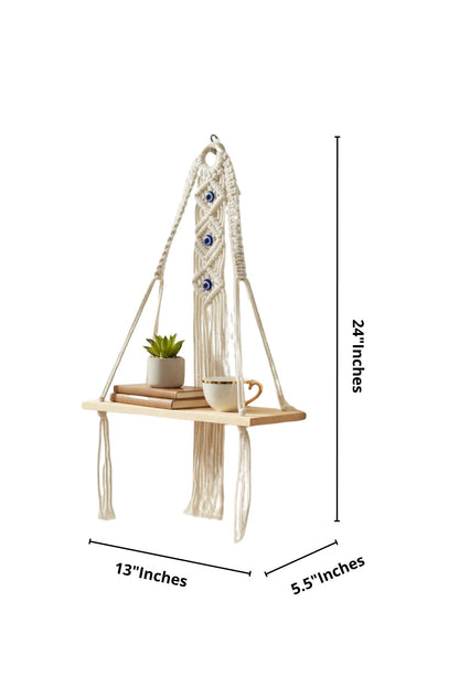 High Objects Zen Series handmade macramé shelf with natural wood, cream rope, and blue evil eye accents. Holds books, plant, and mug.