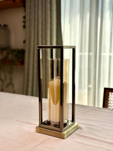 High Objects Modern Halo Frame Candle Stand Set with a tall pillar candle inside a cylindrical glass holder, set on a table.