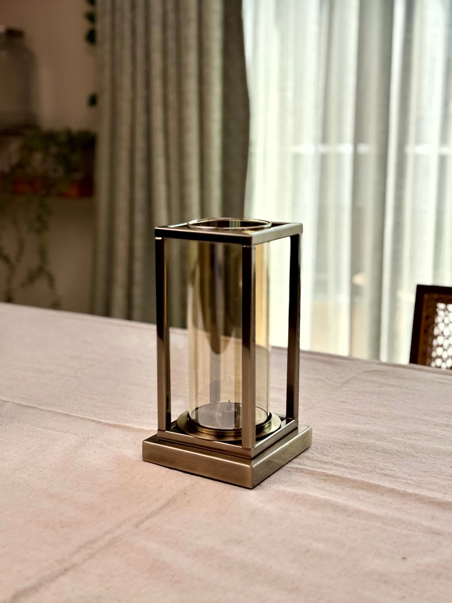 High Objects Modern Halo Frame candle stand with a rectangular metal frame and cylindrical glass chamber, antique brass finish.
