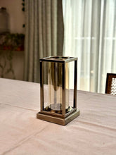 High Objects Modern Halo Frame candle stand with a rectangular metal frame and cylindrical glass chamber, antique brass finish.