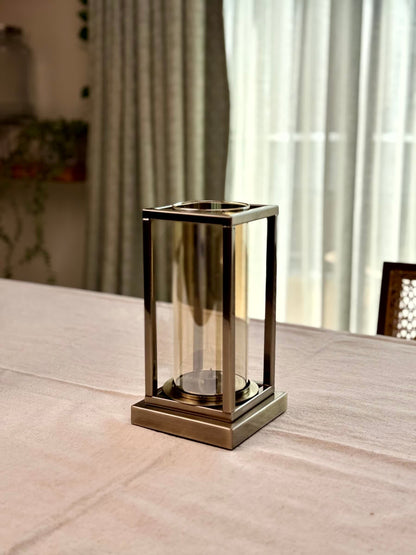 High Objects Modern Halo Frame candle stand with a rectangular metal frame and cylindrical glass chamber, antique brass finish.