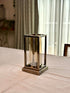 High Objects Modern Halo Frame candle stand with a rectangular metal frame and cylindrical glass chamber, antique brass finish.