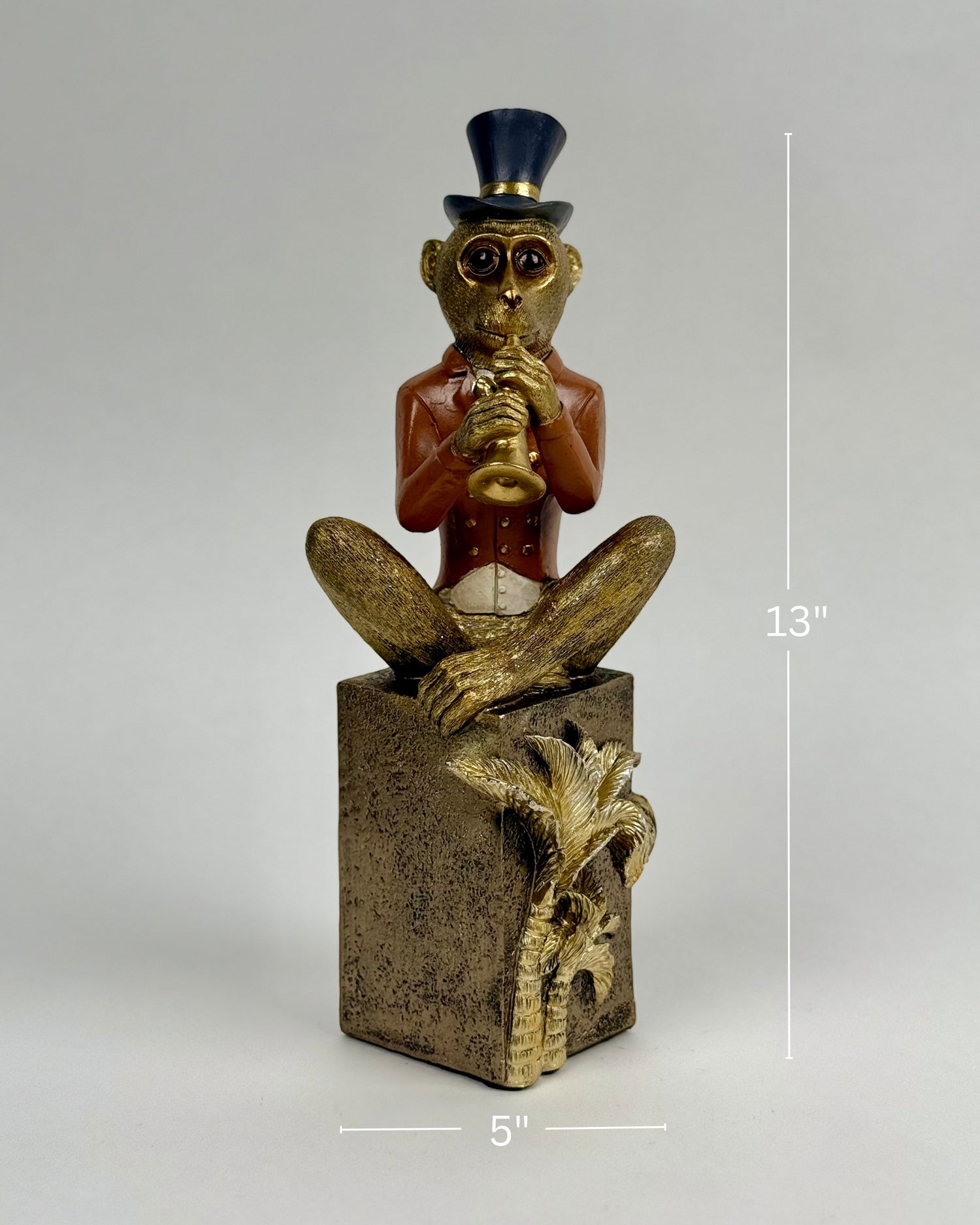 High Objects Golden Serenade Monkey showpiece in a red jacket and top hat playing a trumpet, seated on a textured pedestal.