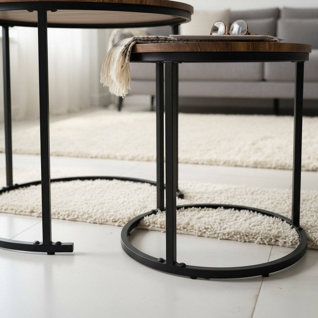 High Objects modern nesting coffee table set with round wood tops and black metal frames. One table holds books and a plant, the other a tablet and glasses.