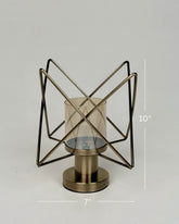 High Objects Nexus Geo Candle Stand, modern geometric metal frame with amber glass cylinder, antique brass finish.
