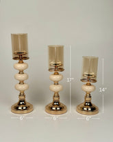 High Objects Opaline Gold Candle Stand Collection set of 3, featuring gold bases, opaline accents, and amber glass shades in varying heights.