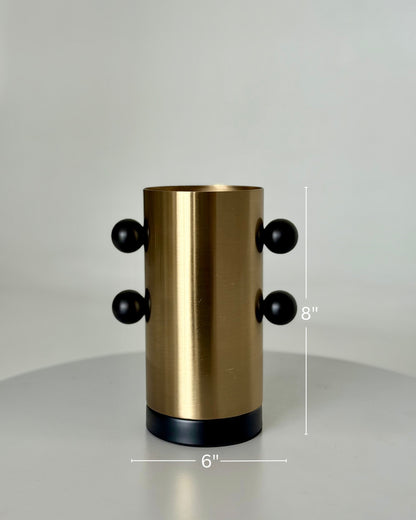 High Objects Orbis Luxe cylindrical gold vase with black orb accents and black base. 8" H x 6" W.