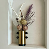 High Objects Orbis Luxe cylindrical gold vase with black orb accents and dried floral arrangement.
