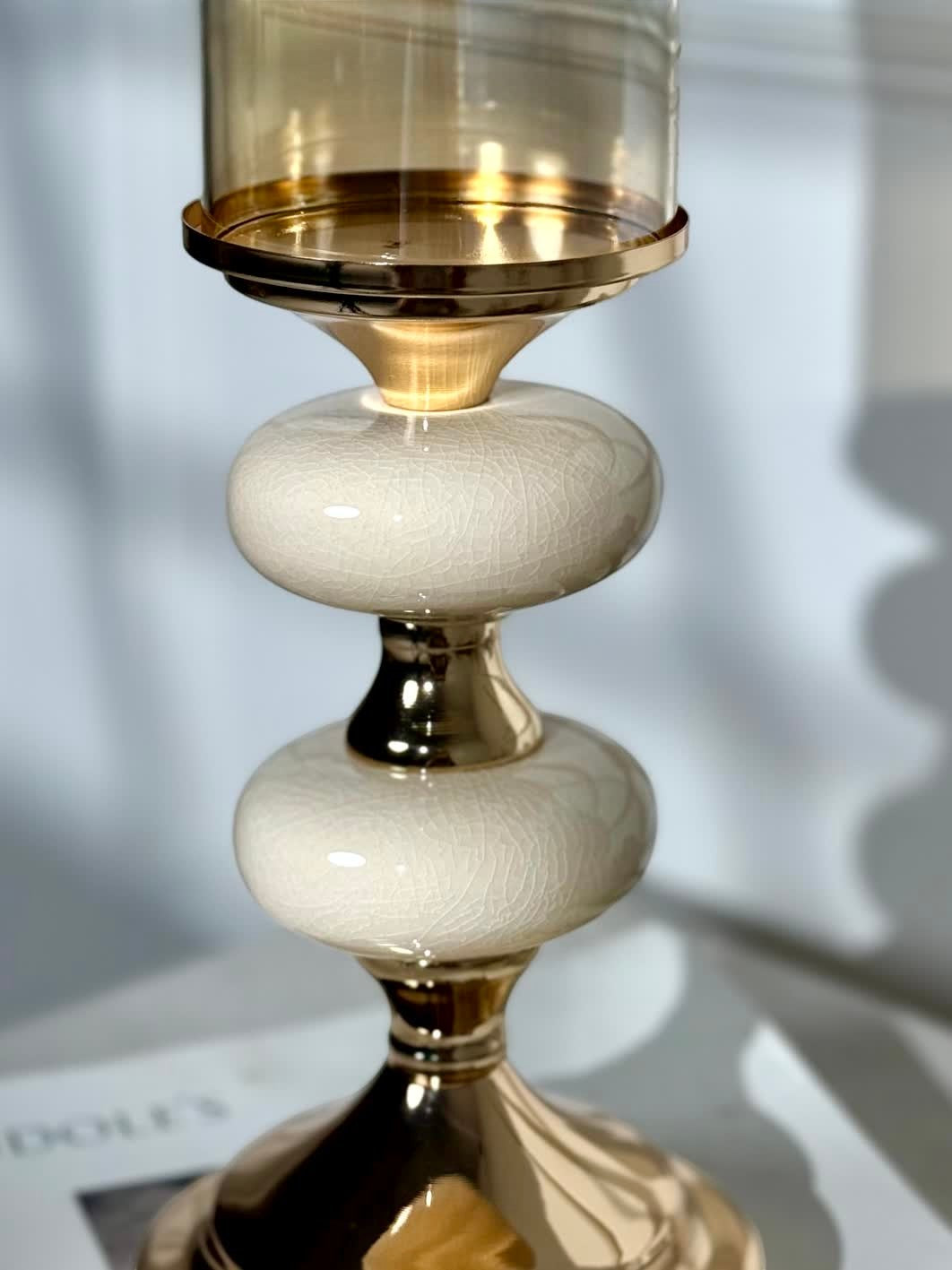 High Objects Pebble Luxe candle stand with cream crackle ceramic and gold accents, topped with amber glass hurricane.