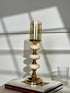 High Objects Pebble Luxe candle stand with gold base, cream pebble accents, and amber glass hurricane.