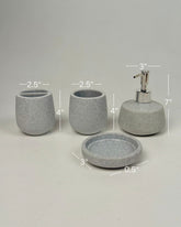High Objects Pebbleease bathroom accessory set in speckled grey resin, includes soap dish, toothbrush holder, cup, and lotion dispenser.