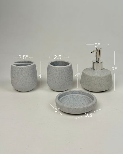 High Objects Pebbleease bathroom accessory set in speckled grey resin, includes soap dish, toothbrush holder, cup, and lotion dispenser.