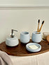 High Objects Pebbleease bathroom accessory set with soap dispenser, toothbrush holder, and soap dish in speckled light blue.