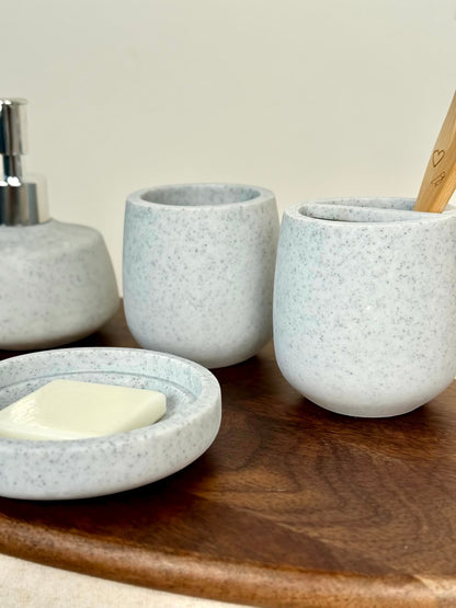 High Objects Pebbleease Bathroom Accessory Set: speckled grey soap dish, dispenser, and toothbrush holder with bamboo toothbrush.