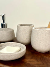 High Objects Pebbleease speckled stone bathroom accessory set with soap dish, soap dispenser, and toothbrush holder.