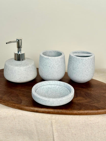High Objects Pebbleease Bathroom Accessory Set: speckled white soap dispenser, toothbrush holder, cup, and dish with rounded silhouettes.