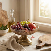 High Objects antique brass pedestal fruit bowl with diamond pattern glass, filled with grapes, figs, pomegranates, and berries.