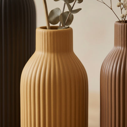 High Objects ribbed ceramic vases in charcoal, ochre, and rust, holding dried botanicals. Modern decor.