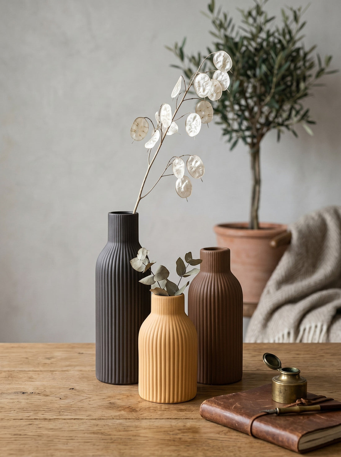 High Objects set of 3 ribbed ceramic vases in black, ochre, and brown. Smallest ochre vase is bulbous, others are tall and slender.