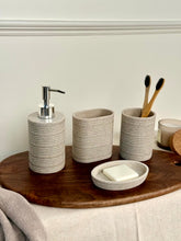 High Objects Ridgeline bathroom accessory set in speckled beige stone with horizontal ridges. Includes soap dispenser, soap dish, and toothbrush holder.