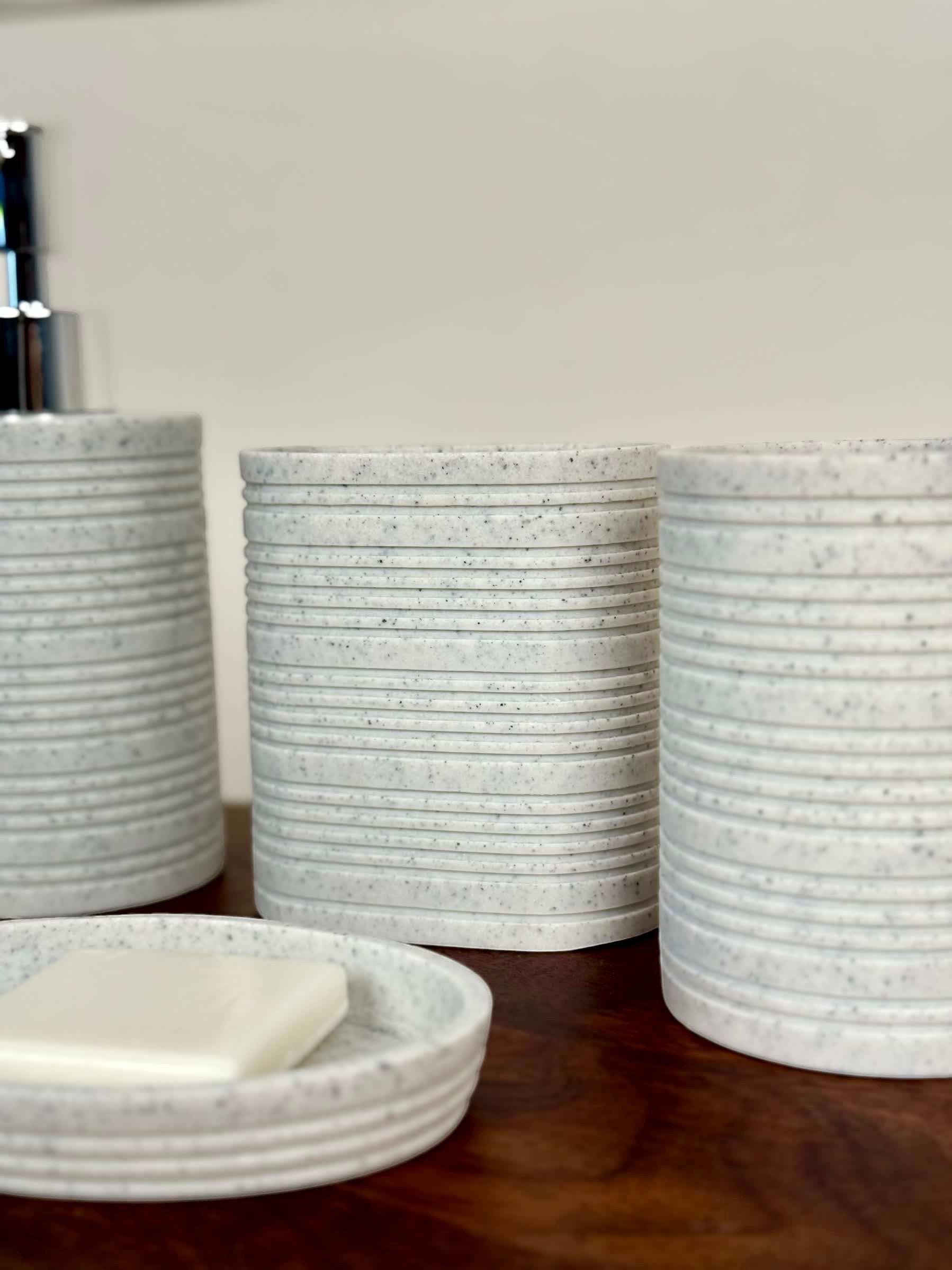 High Objects Ridgeline Bathroom Accessory Set: speckled grey resin soap dish, dispenser, and tumblers with horizontal ridges.