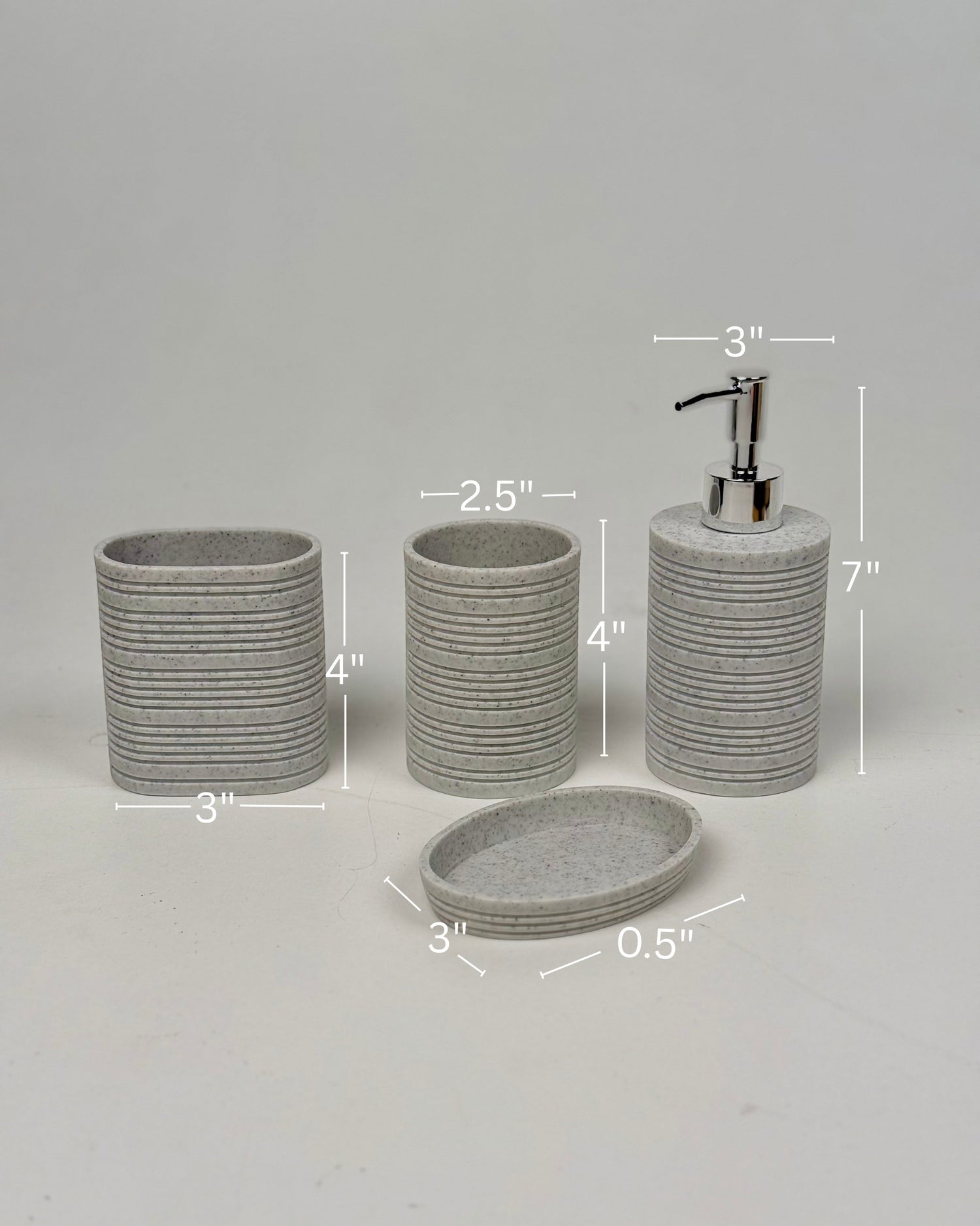 High Objects Ridgeline Bathroom Accessory Set: speckled grey resin soap dispenser, toothbrush holder, cup, and soap dish with horizontal ridges.